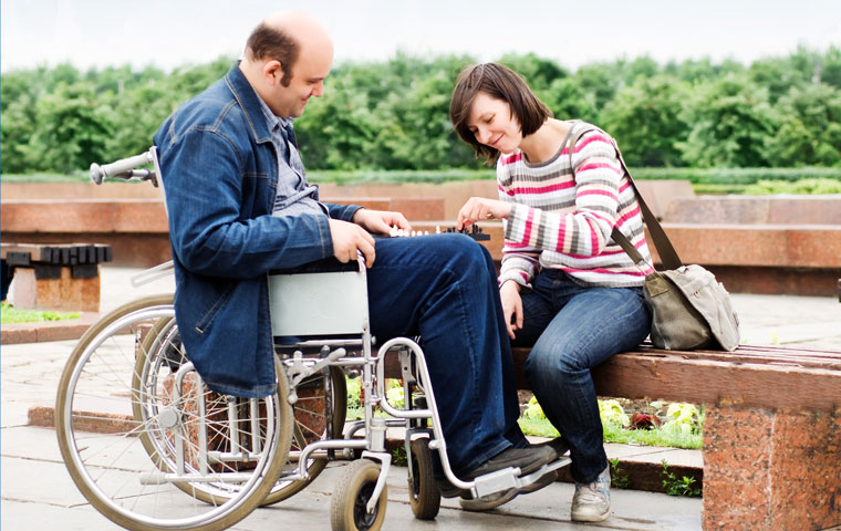 A caregiver in the Syracuse area playa chess with a man in wheelchair as part of her in-home care for disabled adults services.