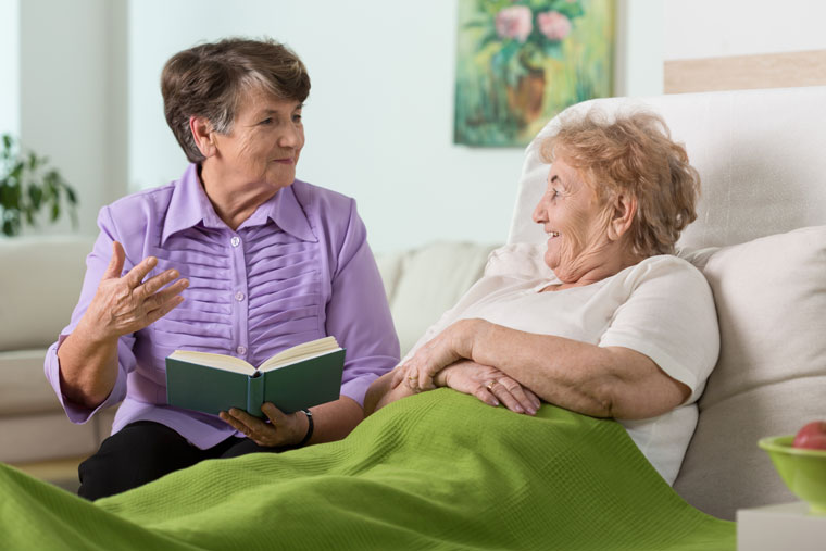 Facility sitter reading book to patient