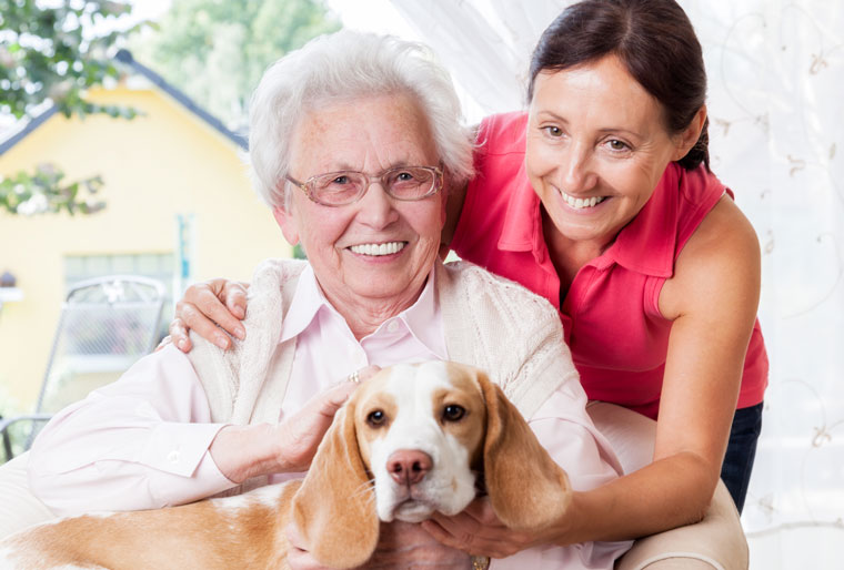 An elderly woman spends time with her dog and a caregiver providing respite care.