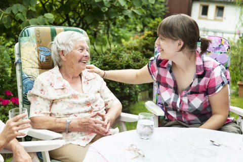 Elderly woman and caregiver sitting outside