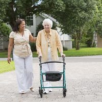 caregiver-with-senior-using-walker-outside