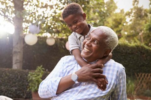A senior man smiles at his grandson as he shows off his smart watch, an innovative piece of home health technology.