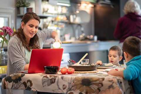 Mothering working and eating at the dining table.