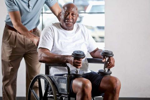 senior man in a wheelchair holding weights