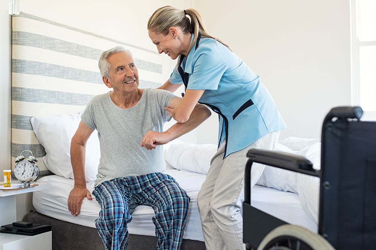 caregiver assisting senior man out of bed