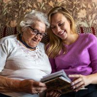 happy-senior-lady-and-caregiver-looking-at-photo-album