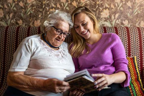 happy-senior-lady-and-caregiver-looking-at-photo-album