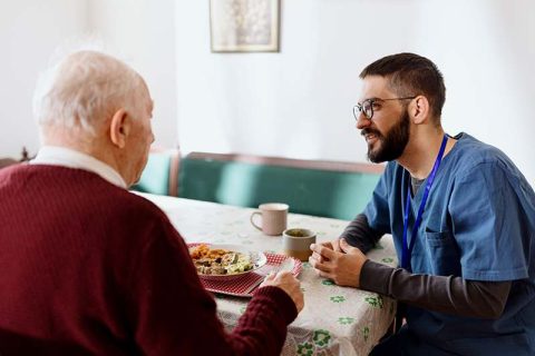 caregiver-encouraging-senior-man-to-eat