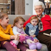 An elderly woman enjoys time with her grandchildren