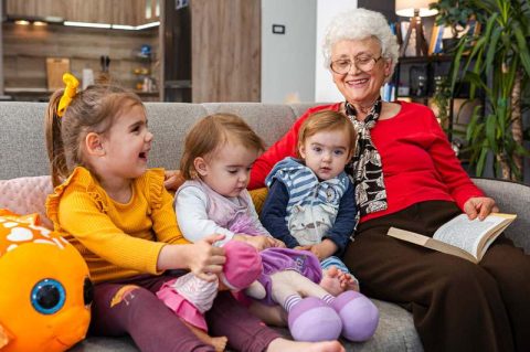 An elderly woman enjoys time with her grandchildren
