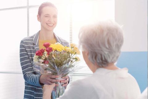 Caregiver giving flowers to senior woman