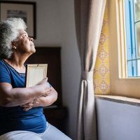 Senior woman hugging a picture of a loved one