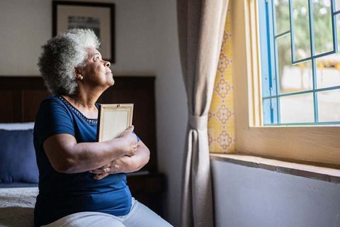 Senior woman hugging a picture of a loved one