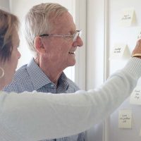 Lady pointing at reminder to help senior with dementia