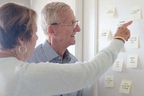 Lady pointing at reminder to help senior with dementia