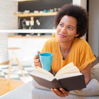 A woman reads and drinks coffee alone to protect her privacy as a caregiver.