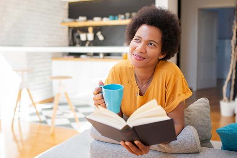 A woman reads and drinks coffee alone to protect her privacy as a caregiver.