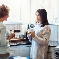 A mom and daughter stand in the kitchen having tough conversations to strengthen family relationships.