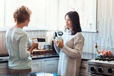 A mom and daughter stand in the kitchen having tough conversations to strengthen family relationships.