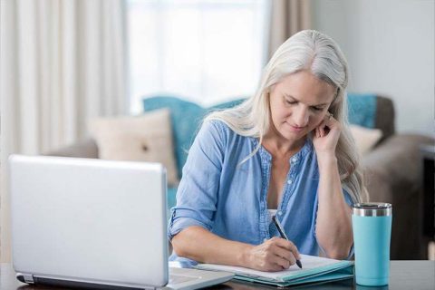 A woman writes down time management tips for caregivers.