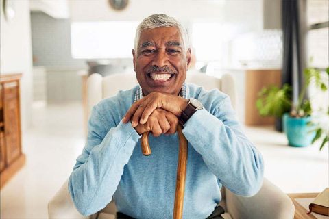 An older adult sits in a chair smiling after overcoming the fear of senior falls.