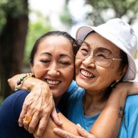 The adult child of someone with dementia hugs her mother as they smile.