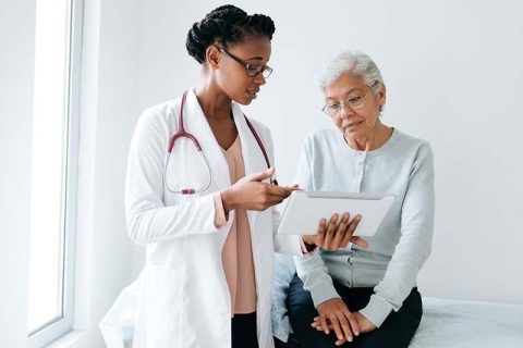 A doctor brings a patient in to discuss a dementia diagnosis with her.